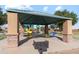 Community picnic area with shaded tables, grill, and nearby playground at 38055 W Bello Ln, Maricopa, AZ 85138