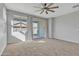 This bedroom boasts carpeted floors, a ceiling fan, and a sliding glass door that opens to the backyard at 41260 W Palmyra Ln, Maricopa, AZ 85138