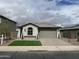 Charming single-story home featuring a desert landscape, lush green lawn, and a two-car garage at 41260 W Palmyra Ln, Maricopa, AZ 85138