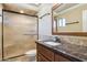 Well-lit bathroom featuring a granite countertop, framed mirror, and glass shower with neutral tile surround at 9120 W Villa Lindo Dr, Peoria, AZ 85383