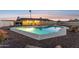 Backyard view of a home showcasing a large, uniquely-shaped pool and relaxing desert landscaping against a colorful sky at 9120 W Villa Lindo Dr, Peoria, AZ 85383