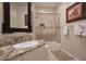 Elegant bathroom features granite counters, a framed mirror, and a shower over tub with glass doors at 10222 E Southwind Ln # 1054, Scottsdale, AZ 85262