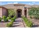 Charming entrance to a single story home with a stone archway, complemented by manicured shrubs and a paved walkway at 1096 W Via De Palmas --, San Tan Valley, AZ 85140