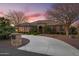 Stunning single-story home featuring a private driveway and a meticulously landscaped front yard with mature trees at sunset at 1096 W Via De Palmas --, San Tan Valley, AZ 85140