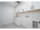 Well-lit laundry room featuring white cabinets, a modern sink, and patterned tile floors at 1120 W Barrow Dr, Chandler, AZ 85224