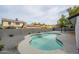 Clear blue swimming pool with surrounding gray gravel and a high block wall and homes in the background at 1120 W Barrow Dr, Chandler, AZ 85224