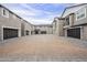 View of residential architecture featuring gray stucco exteriors, garages, and a paved courtyard area at 11300 N Casa Dega Dr # 1020, Surprise, AZ 85388