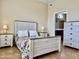 Bright bedroom features a bed with a floral comforter, bedside tables, lamps and dresser set on tile flooring at 14575 W Mountain View Blvd # 11313, Surprise, AZ 85374