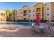 Community pool featuring tables with chairs and umbrellas for shade, with multiple buildings in background at 14575 W Mountain View Blvd # 11313, Surprise, AZ 85374