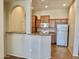 A view of the kitchen featuring wood cabinets, white appliances and a breakfast bar open to another room at 14575 W Mountain View Blvd # 11313, Surprise, AZ 85374