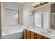 Bathroom with dual sink vanity, large mirror, soaking tub, and natural light at 1473 W Flamingo Dr, Chandler, AZ 85286