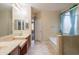 Bright bathroom featuring double sinks, bathtub, and glass shower stall at 15290 W Ventura St, Surprise, AZ 85379
