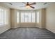 Spacious bedroom with neutral carpet features plantation shutters and a modern ceiling fan at 15290 W Ventura St, Surprise, AZ 85379