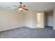 Bedroom with neutral colored walls and carpet features a ceiling fan and an open doorway at 15290 W Ventura St, Surprise, AZ 85379