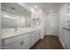 Elegant bathroom features double sinks, white cabinets, and a large mirror, complemented by wood-look flooring at 17310 W Via Dona Rd, Surprise, AZ 85387