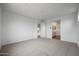 Bright bedroom with neutral carpet and paint, multiple windows, and hallway access to a bathroom at 17310 W Via Dona Rd, Surprise, AZ 85387