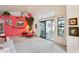 Bright living room with neutral carpet, a red accent wall, comfortable furniture, and access to patio at 19835 N Alta Loma Dr, Sun City West, AZ 85375