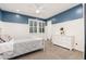 A charming bedroom with gray carpet, a comfortable bed, a vintage phonograph, and shuttered windows at 20088 E Maya Rd, Queen Creek, AZ 85142