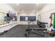Well-equipped home gym featuring weights, inversion table, mounted TV, and rubber flooring at 20088 E Maya Rd, Queen Creek, AZ 85142