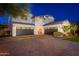 Beautiful home with a paver driveway, three-car garage, professional landscaping, and exterior lighting at twilight at 20088 E Maya Rd, Queen Creek, AZ 85142