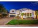 Stunning two-story home featuring lush landscaping, a paver driveway, and exterior lighting at twilight at 20088 E Maya Rd, Queen Creek, AZ 85142