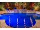 Beautiful blue pool with a cascading waterfall feature and lush, landscaped surroundings at 20088 E Maya Rd, Queen Creek, AZ 85142