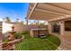 Backyard retreat with a hot tub, charming fountain, and synthetic turf, all sheltered by a slatted pergola at 20215 N Broken Arrow Dr, Sun City West, AZ 85375