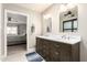 Bathroom with dual sinks, dark wood cabinets, framed mirrors, and an ensuite bedroom at 20215 N Broken Arrow Dr, Sun City West, AZ 85375