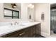 Bathroom with dual sinks, dark wood cabinets, framed mirrors, and shower at 20215 N Broken Arrow Dr, Sun City West, AZ 85375
