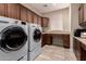 Well-equipped laundry room with modern washer and dryer, desk and ample cabinet space for organized functionality at 229 E Alcatara Ave, Queen Creek, AZ 85140