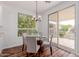 Bright dining area featuring a glass table, modern chandelier, and sliding glass doors to a paved patio at 24812 S Pleasant Ct, Sun Lakes, AZ 85248
