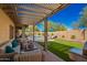 Inviting covered patio with wicker furniture, pergola, and a view of the pool and landscaped backyard at 26991 N 97Th Ln, Peoria, AZ 85383