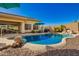 Stunning backyard pool featuring an attached spa, lush palms, and a relaxing desert landscape at 26991 N 97Th Ln, Peoria, AZ 85383