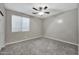 Bright bedroom features a large window, ceiling fan, and plush carpeting, creating a cozy atmosphere at 3220 N 136Th Dr, Avondale, AZ 85392