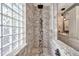 Stone tiled walk-in shower featuring a stone pebble accent strip and glass block window at 3220 N 136Th Dr, Avondale, AZ 85392