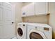 Bright laundry room featuring a white washer and dryer, cabinets, and a door at 3682 S Rosemary Dr, Chandler, AZ 85248
