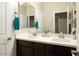 Bathroom featuring double sinks with dark wood cabinets and a large well-lit mirror at 4084 E Rawhide St, Gilbert, AZ 85296