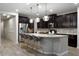Well-lit kitchen features dark cabinets, a stainless steel fridge, a large island, and pendant lighting at 4084 E Rawhide St, Gilbert, AZ 85296