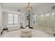 Bright bathroom featuring soaking tub, walk-in glass shower, chandelier lighting, and large ottoman at 4743 N 54Th St, Phoenix, AZ 85018