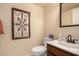 Well-lit half bath featuring neutral colors, a sink with bronze hardware, and decorative wall art at 5518 E Lindstrom Ln # 2011, Mesa, AZ 85215