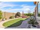 Lush backyard featuring artificial turf, desert landscaping, and paver walkway, all enclosed by block fencing at 5942 W Cactus Wren Way, Florence, AZ 85132