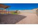 Spacious backyard featuring a playset, gravel, partial patio cover, and block fence for added privacy at 8430 W Atlantis Way, Tolleson, AZ 85353