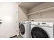 Convenient laundry room with modern, front-load washer and dryer units and overhead shelving at 8430 W Atlantis Way, Tolleson, AZ 85353