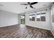 Open-concept living room with wood-look floors, ceiling fan, large windows and sliding door to the backyard at 10024 E Tamery Ave, Mesa, AZ 85212