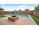 A backyard oasis with a sparkling pool, modern firepit, and lush landscaping at 10024 E Tamery Ave, Mesa, AZ 85212