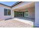 A covered patio with neutral colors, stone ground covering, and sliding glass doors to let natural light in at 11188 N Blakely St, Surprise, AZ 85388