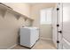 Bright laundry room with white washer, dryer, overhead shelving, and tile floor at 11915 S 184Th Ave, Goodyear, AZ 85338