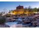 Beautiful water feature with cascading waterfalls, rocks, and desert landscaping at twilight at 11915 S 184Th Ave, Goodyear, AZ 85338