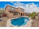 A backyard with a uniquely shaped swimming pool, lush landscaping, and patio at 15322 W Montecito Ave, Goodyear, AZ 85395