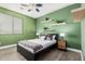 Bedroom featuring bright green accent wall, floating shelves with plants, and a ceiling fan at 15322 W Montecito Ave, Goodyear, AZ 85395